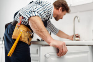 Selective focus of plumber in tool belt repairing kitchen faucet