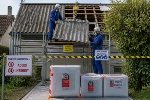 Professionnels protégés retirant une toiture en fibrociment amianté avec précaution, zone sécurisée et déchets conditionnés.